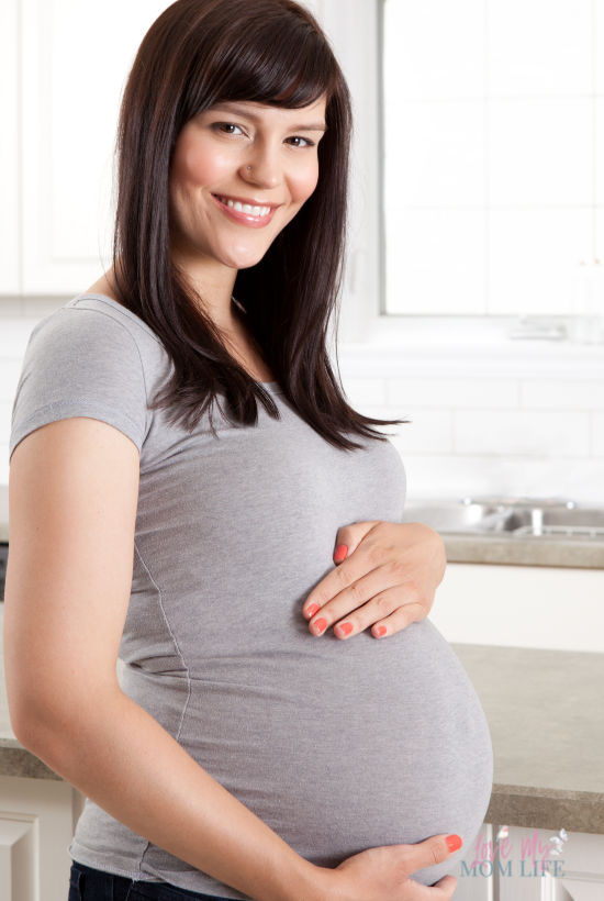 Brown haired pregnant woman looking at camera and smiling.